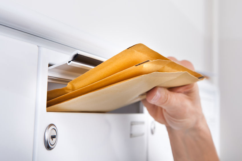 25150080 – close-up of postman putting letters in mailbox