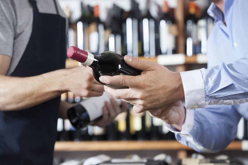 61809614 – midsection of male customer and salesman with wine bottles in shop
